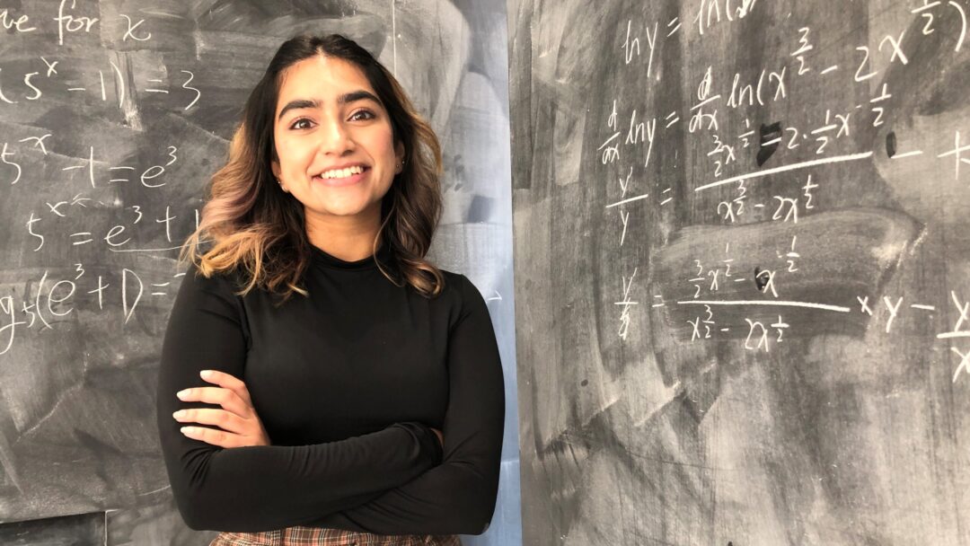 Student in front of chalk board.